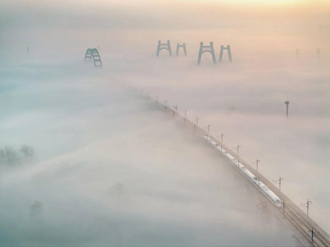 云端高铁来,摄影苗地。2024年11月22日,在寿县古城的上空,平流云如轻柔的纱幔,缓缓铺展。一列高速列车恰如银色的蛟龙,划破这黎明的寂静,呼啸着驶过。.jpg